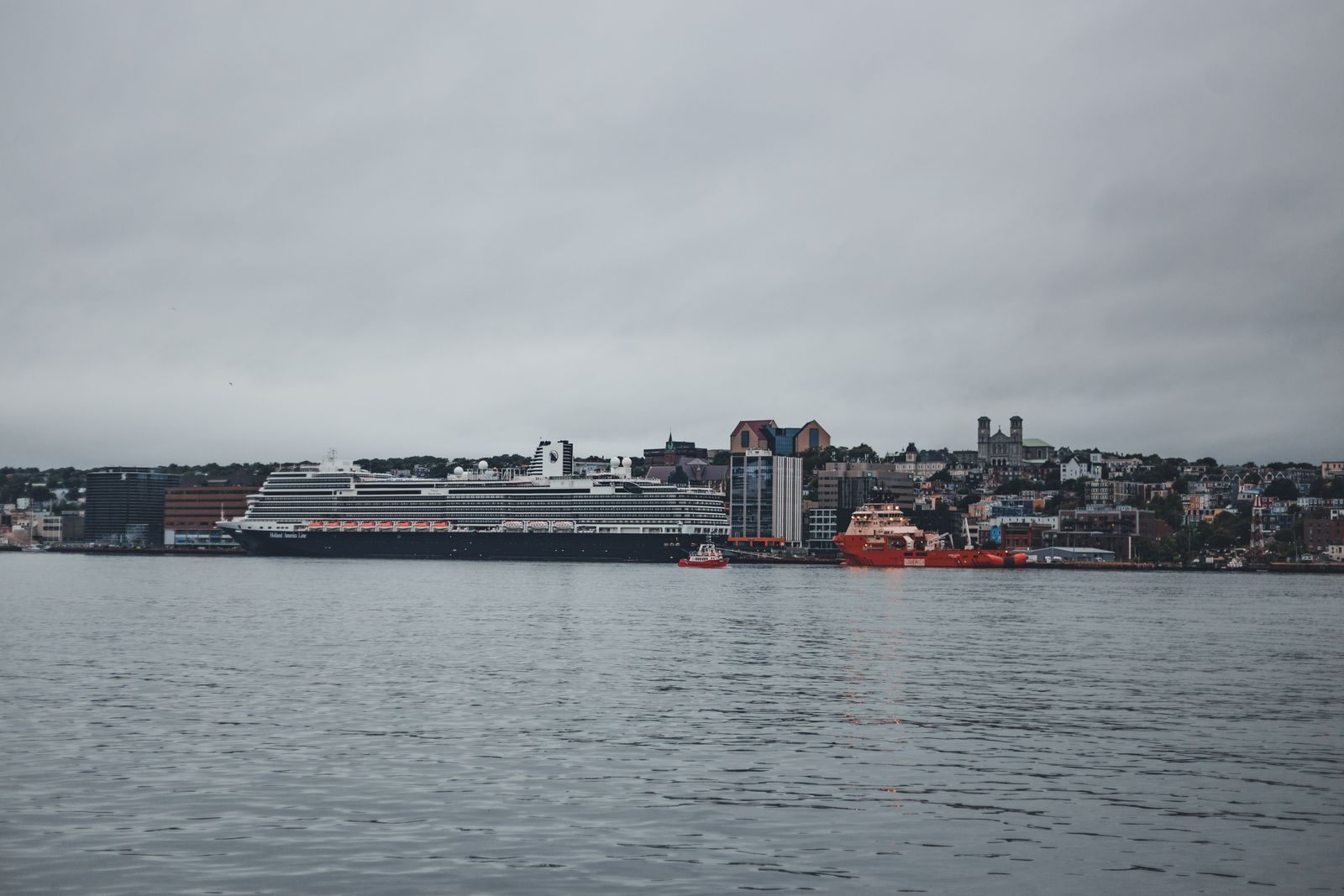 Cruise ship moored beside a hillside city, the kind of vessel agents compare by cruise ship classes by size