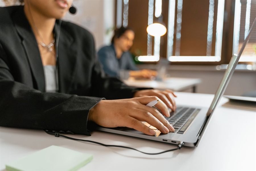 Agent with a headset typing on a laptop